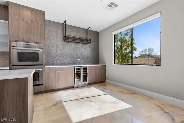 kitchen with wine cooler, marble finish floor, light countertops, double oven, and baseboards