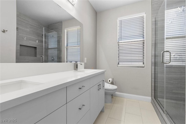 full bathroom featuring double vanity, a stall shower, baseboards, toilet, and a sink