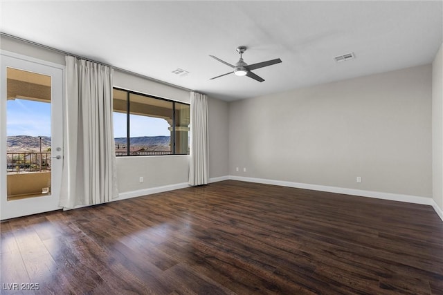 empty room featuring dark wood-style floors, a wealth of natural light, and visible vents