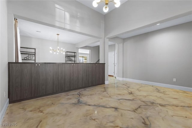 interior space featuring baseboards, concrete flooring, and a notable chandelier