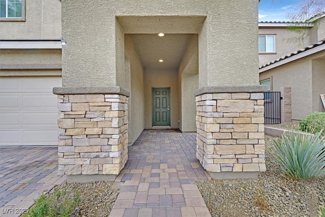 property entrance with a garage, visible vents, and stucco siding