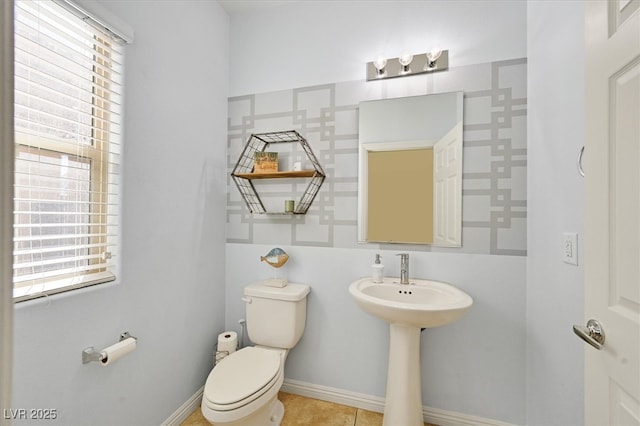 half bathroom with tile patterned floors, toilet, and baseboards