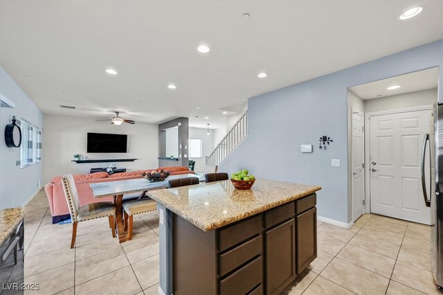 kitchen with light stone counters, light tile patterned floors, recessed lighting, a ceiling fan, and a kitchen island