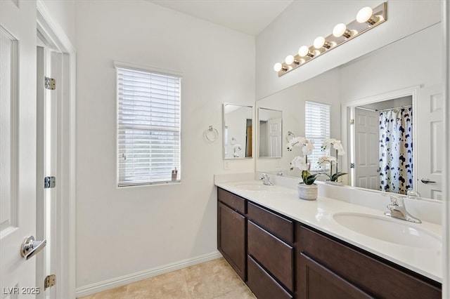 bathroom with tile patterned flooring, a sink, baseboards, and double vanity