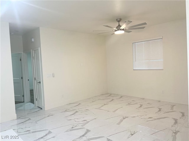 unfurnished room with a ceiling fan and marble finish floor