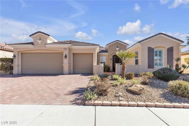 view of front of home featuring decorative driveway, an attached garage, and stucco siding