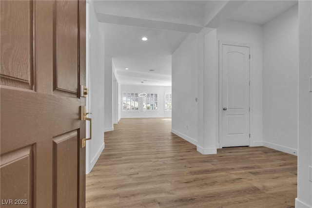 corridor featuring light wood-type flooring, baseboards, and recessed lighting