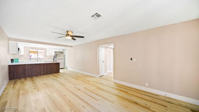 interior space with visible vents, open floor plan, light countertops, a peninsula, and white appliances