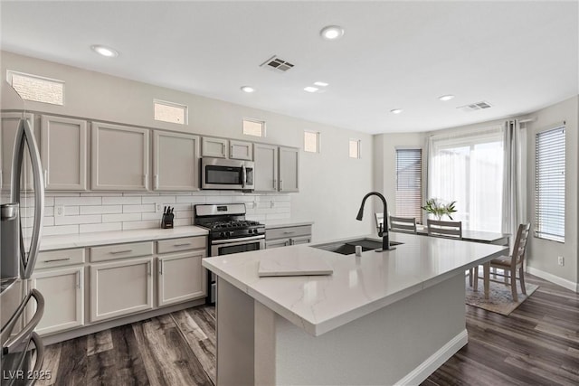 kitchen featuring an island with sink, gray cabinets, sink, and stainless steel appliances