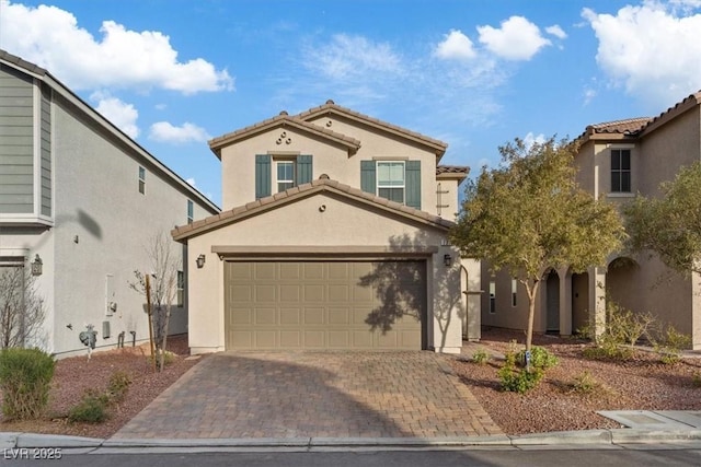 mediterranean / spanish-style home featuring decorative driveway, a tiled roof, an attached garage, and stucco siding