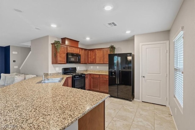 kitchen featuring light stone countertops, black appliances, light tile patterned floors, sink, and kitchen peninsula