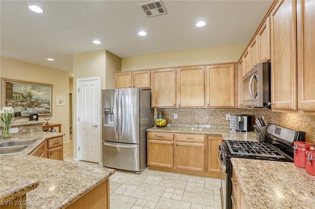 kitchen featuring appliances with stainless steel finishes, sink, backsplash, and light stone counters