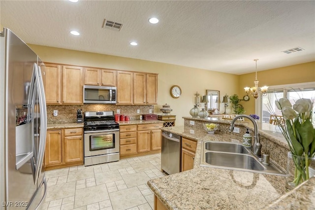 kitchen featuring appliances with stainless steel finishes, pendant lighting, backsplash, sink, and an inviting chandelier