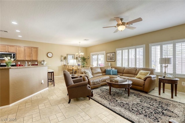 living room featuring ceiling fan with notable chandelier and a textured ceiling