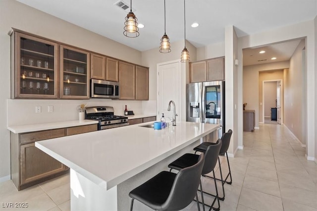 kitchen with sink, stainless steel appliances, a kitchen island with sink, and a breakfast bar