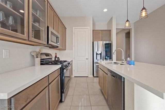 kitchen featuring decorative light fixtures, an island with sink, stainless steel appliances, and sink