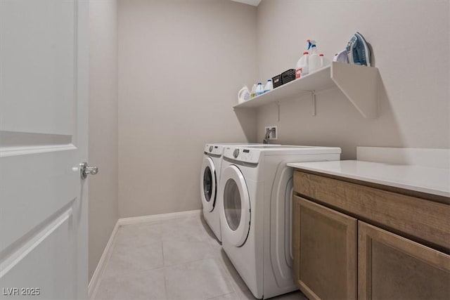 laundry room featuring light tile patterned floors, washer and clothes dryer, and cabinets