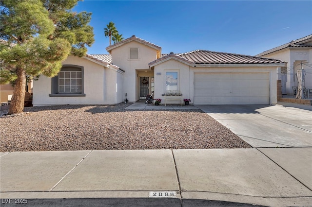 mediterranean / spanish-style house with concrete driveway, a tile roof, an attached garage, and stucco siding