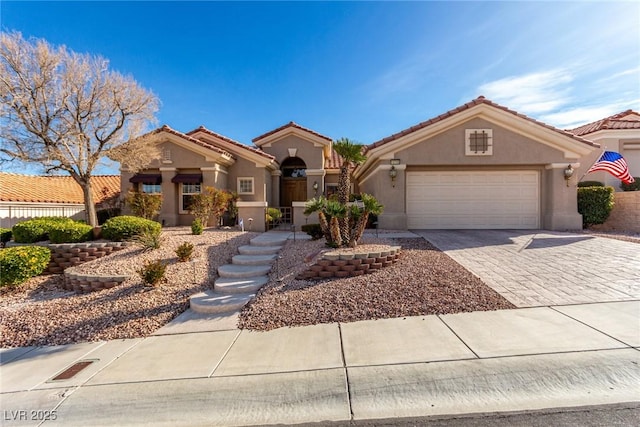 mediterranean / spanish-style house featuring a tiled roof, decorative driveway, an attached garage, and stucco siding