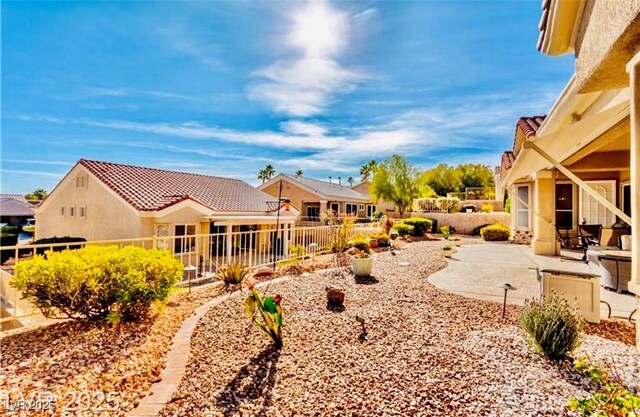 rear view of house with a patio, a tile roof, a fenced backyard, and stucco siding