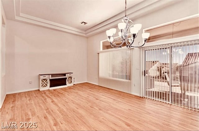 unfurnished dining area with baseboards, wood finished floors, visible vents, and an inviting chandelier