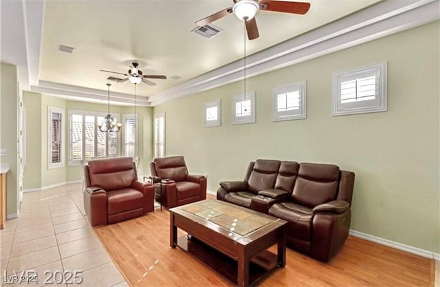 living room featuring ceiling fan with notable chandelier, visible vents, and baseboards