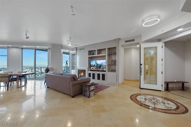 living room featuring ceiling fan and built in shelves