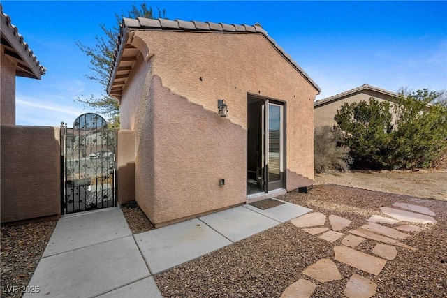 rear view of property with a gate and stucco siding