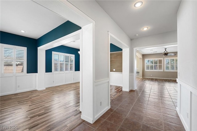 interior space with ceiling fan, wainscoting, and a healthy amount of sunlight