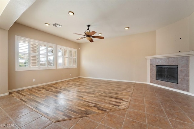 unfurnished living room with a tile fireplace, recessed lighting, wood finished floors, visible vents, and baseboards