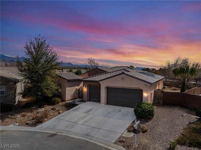 view of front facade with stucco siding, an attached garage, fence, driveway, and a tiled roof