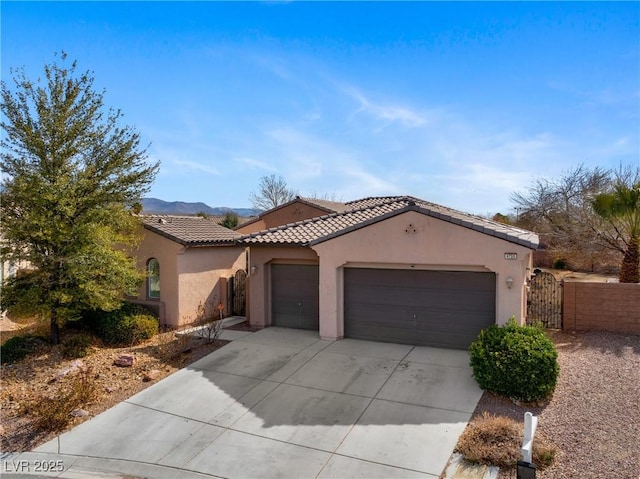 mediterranean / spanish-style house featuring driveway, an attached garage, a gate, and stucco siding