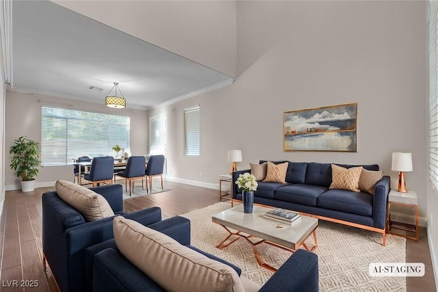 living room featuring hardwood / wood-style floors, ornamental molding, and a towering ceiling