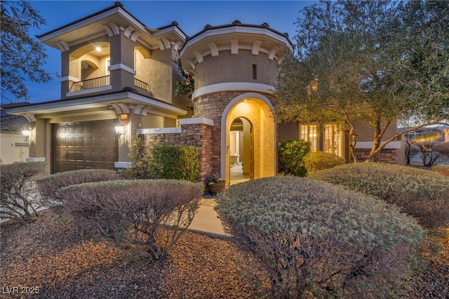 view of front facade featuring an attached garage, stone siding, and stucco siding