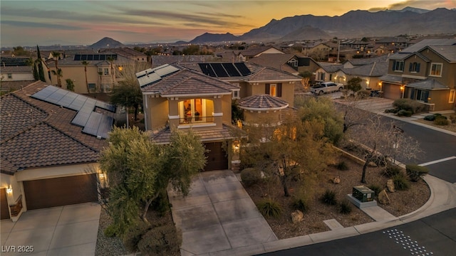 view of front of house featuring roof mounted solar panels, a mountain view, concrete driveway, and a residential view