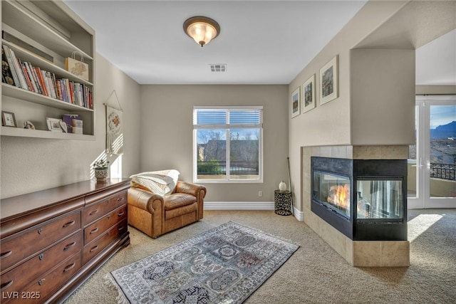 living area featuring baseboards, visible vents, light carpet, and a tiled fireplace