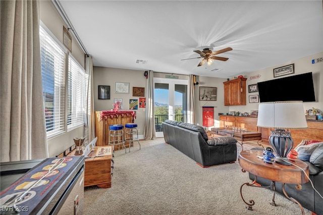 living area featuring light carpet, ceiling fan, and visible vents