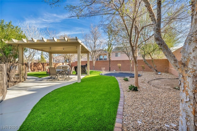 view of yard featuring a trampoline, a patio area, and a fenced backyard