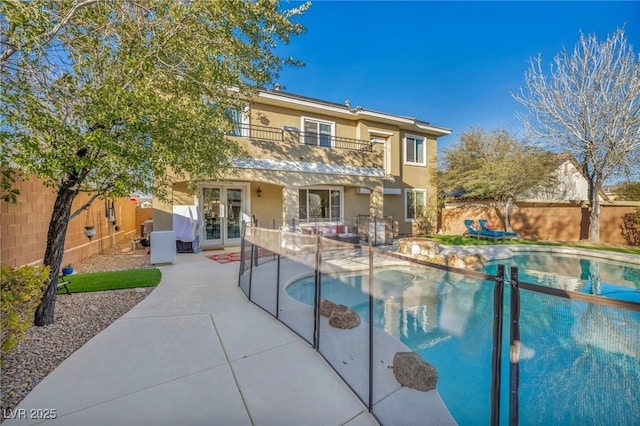 view of pool featuring french doors, a patio area, a fenced backyard, and a fenced in pool