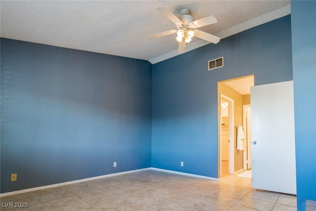 spare room featuring visible vents, ceiling fan, vaulted ceiling, a textured ceiling, and light tile patterned flooring