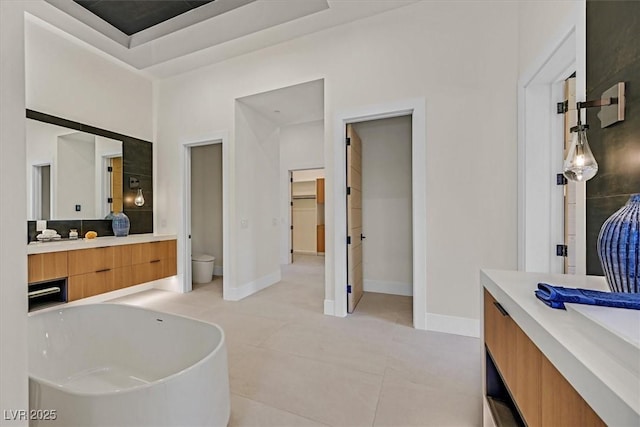 bathroom with tile patterned flooring, a high ceiling, toilet, a bathing tub, and vanity