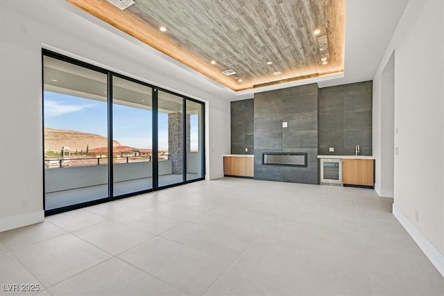 unfurnished living room featuring a fireplace, sink, a mountain view, wooden ceiling, and a raised ceiling