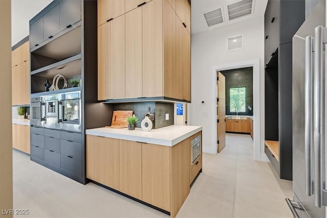 kitchen featuring sink, high end fridge, wall oven, light brown cabinetry, and tasteful backsplash