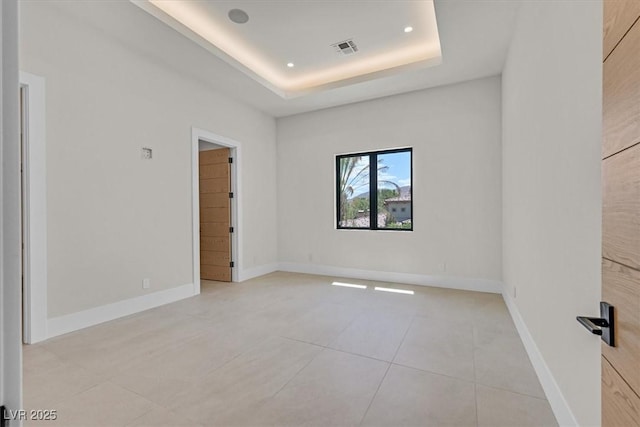 spare room featuring a towering ceiling, light tile patterned flooring, and a raised ceiling