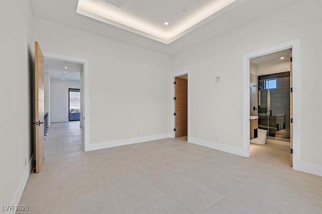 empty room with a tray ceiling and light tile patterned floors