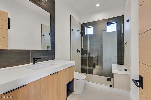 bathroom featuring tile patterned floors, toilet, vanity, and a shower with shower door
