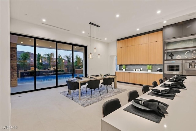 kitchen with a breakfast bar area, decorative light fixtures, decorative backsplash, a center island, and oven