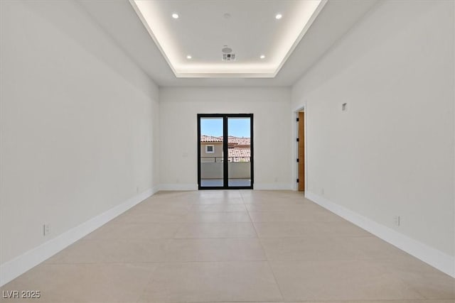 unfurnished room with a tray ceiling and light tile patterned flooring