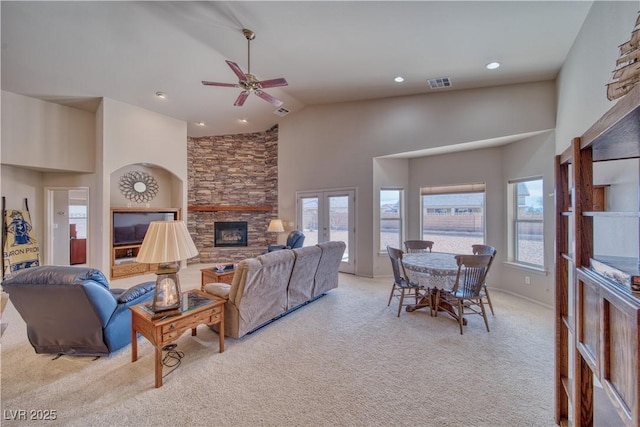 carpeted living room featuring a fireplace, french doors, high vaulted ceiling, and a healthy amount of sunlight