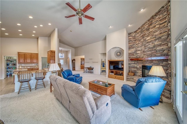 living room with a fireplace, light carpet, high vaulted ceiling, and ceiling fan